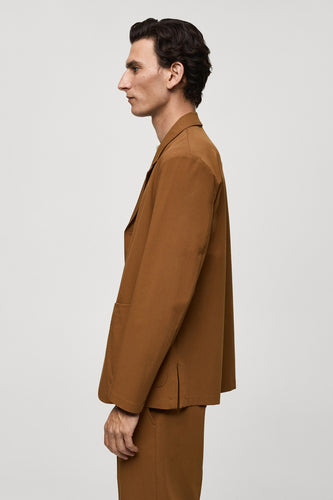 Oranje blazer van MANGO, getoond in zijaanzicht met een bijpassende broek.