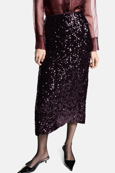 Robe rouge de MANGO, avec paillettes et une fente, vue de côté avec une blouse transparente et des talons.