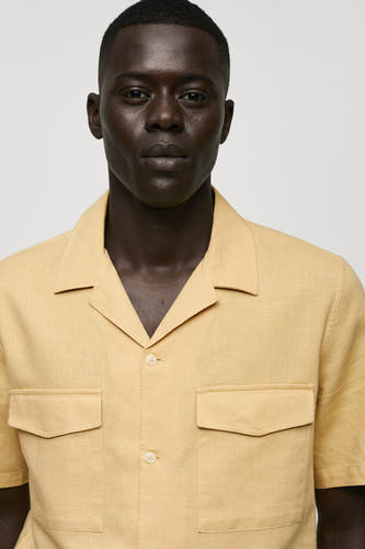 Geel overhemd met korte mouwen van MANGO, met borstzakken en knoopsluiting, close-up.
