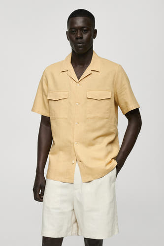 Jaune, t-shirt à manches courtes de MANGO en vue de dos, avec des shortis blancs et des sandales.