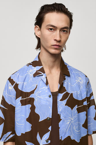 Chemise de fleurs bleues et brunes MANGOANGO, man courtestestes et une chemise brune en dessous.
