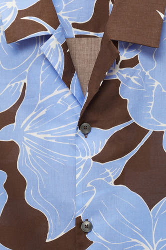 Chemise à fleurs brune de MANGO, avec des manches courtes et un motif floral distinctif en bleu et blanc.