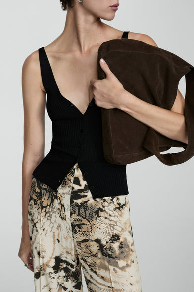 Pantalon beige de MANGO, avec un motif abstrait de peau de serpent et associé à une chemise noire à col it.
