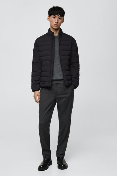 Manteau court noir de MANGO, vu de derrière, avec des coutures horizontales et un pantalon uni.