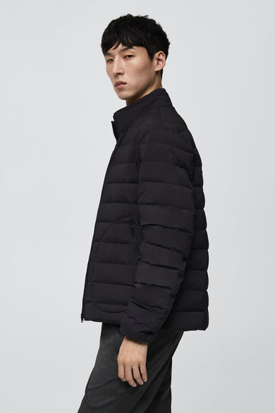 Manteau gris court de MANGO, avec des coutures horizontales et porté sur un pantalon foncé.