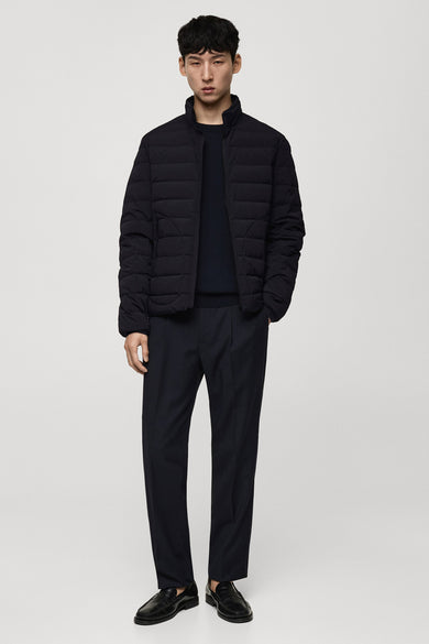 Manteau bleu court de MANGO porté avec un pull sombre et un pantalon, et des chaussures noires.