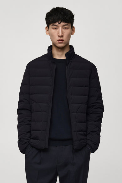 Manteau bleu court de MANGO porté sur un pull et un pantalon bleu marine.