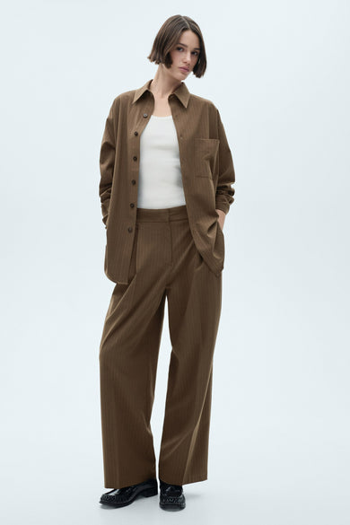 Blazer vert de MANGO, gedragen met een witte top en een bruine gestreepte broek.