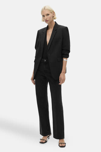 Jean droit gris anthracite de MANGO avec des détails discrètement scintillants, associé à un blazer noir et à des sandales à talons.
