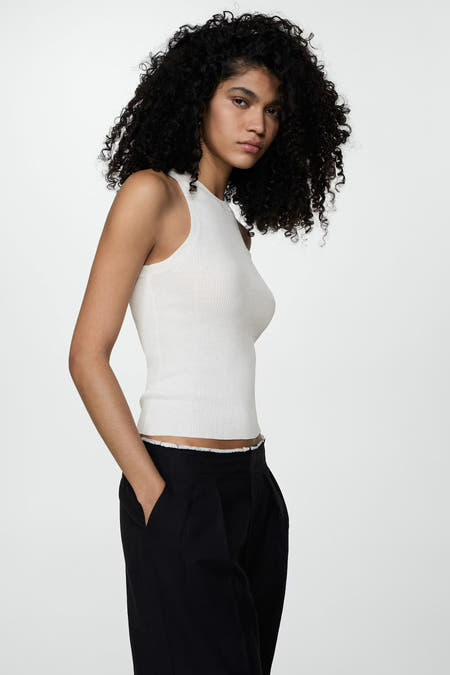 Sous-vêtement beige de MANGO, dos, porté avec un pantalon noir et des cheveux bouclés.