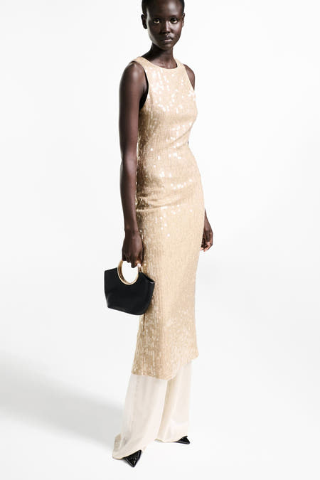 Robe sans manches dorée de MANGO, avec paillettes et une poche main noire des détails dorés.