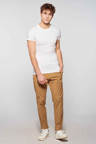 Man in witte T-shirt en bruine broek.