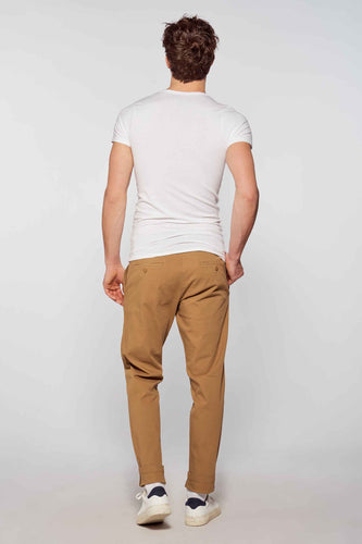 Homme de dos, t-shirt blanc, chino marron, baskets blanches.