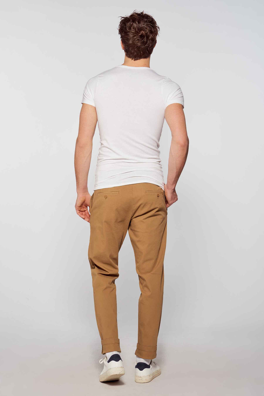 Homme de dos, t-shirt blanc, chino marron, baskets blanches.