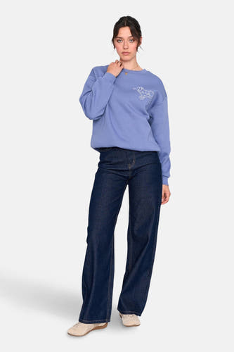 Jean denim bleu marine large de 24 couleurs GMBH, avec des jambes larges et associé à un pull bleu et des chaussures beige.