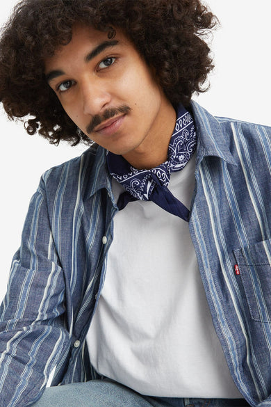 Chemise rayée bleue de Levi's avec longues manches, avec un bandana autour du cou et un t-shirt blanc en dessous.