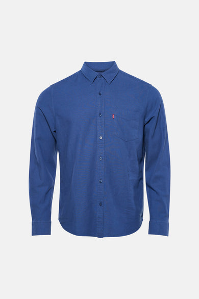 Chemise bleue à manches longues Levi's®, avec fermeture boutonnée et poche poitrine, associée à un pantalon noir et des mocassins en daim.