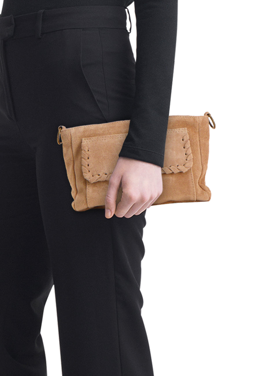 Sac à bandoulière en suède beige d'Access® avec surpiqûres tressées sur le rabat, tenu contre un pantalon noir.