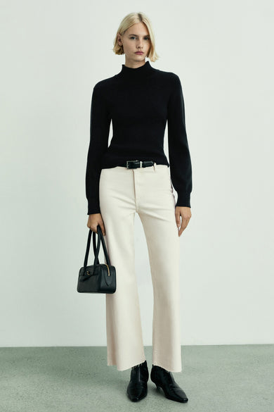 Jean blanc cassé large de MANGO, associé à une veste noire, un ceinture et un sac main, avec des chaussures noires.