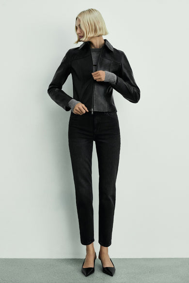 Jean mom marron foncé de MANGO, associé à une veste en cuir noire et à un pull gris.
