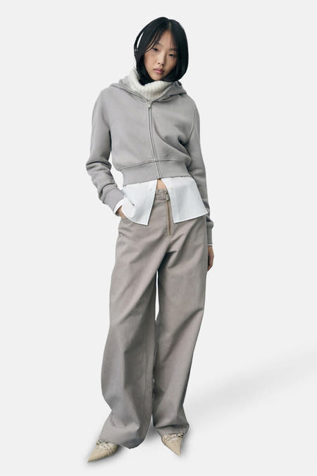 Pantalon beige de MANGO, avec des jambes larges et une tenue avec un t-shirt blanc et une hoodie.