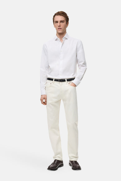 Blouse blanche à manches longues de MANGO, portée avec une ceinture noire et des jeans beiges et des chaussures marron.