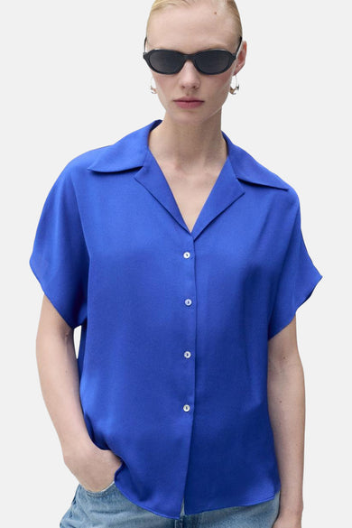 Chemise bleue à manches courtes de MANGO, vue de l'arrière avec des jeans bleu clair.