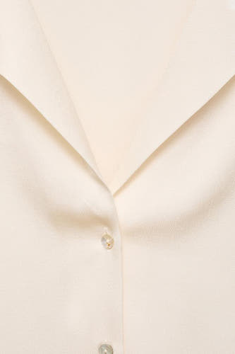 Chemise écru à manches courtes de MANGO, avec un col ouvert et une fermeture à boutons.