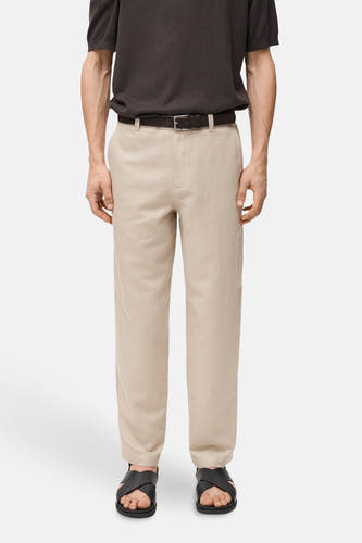 Pantalon écru de MANGO, porté avec une ceinture marron et des sandales noires.