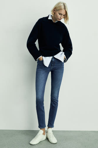 Jean skinny en denim mid-blue de MANGO, porté avec un un-shirt et des sneakers blanches.