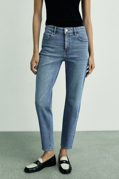 Jean mom bleu mid de MANGO, dos, associé à une chemise noire et des loafers noirs.