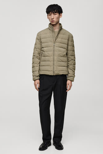 Manteau court gris de MANGO, porté avec un pull beige et un pantalon noir.