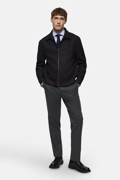 Gilet bleu de MANGO porté sur une chemise bleue claire à col cravate et un pantalon gris.