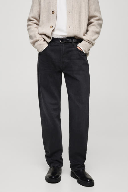 Jean denim bleu marine foncé de MANGO, avec une ceinture noire, associé à un cardigan beige et des chaussures noires.