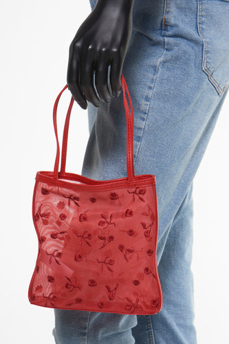 Rode handtas met bloemenmotief, blauwe jeans, mannequin.
