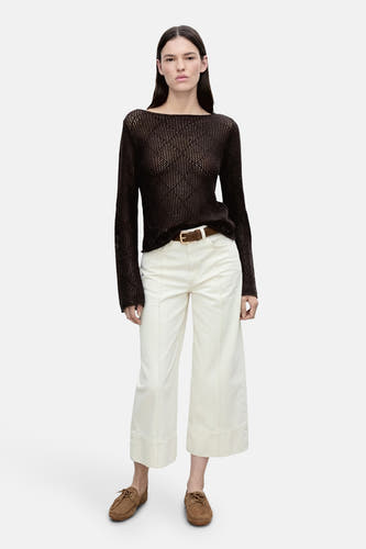 Pull marron avec col rond de MANGO, porté avec un pantalon blanc, une ceinture marron et des mocassins.