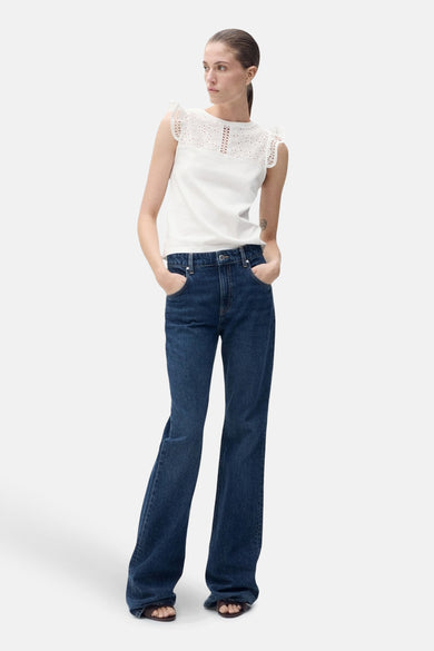 T-shirt sans manches blanc de MANGO avec des bordures sur les épaules, porté avec des jeans noirs à jambes larges.