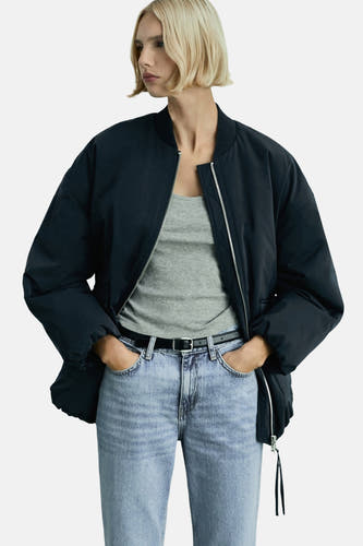 Jean bleu clair droit de MANGO, porté avec une ceinture noire et un haut gris sous un manteau bleu foncé.