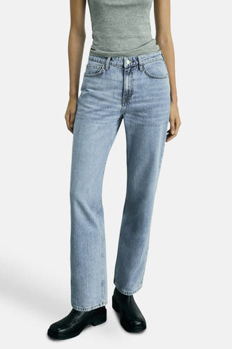 Jean bleu clair droit de MANGO, associé à un tank-top gris et des bottes noires, posé au sol.