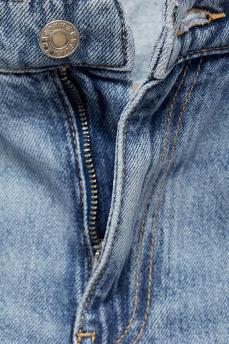 Jean droit en denim bleu clair de MANGO, avec une fermeture éclair argentée et une fermeture à gliss.