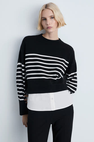 Pull-over noir avec col rond de MANGO, design rayé avec du blanc, associé à une chemise blanche et un pantalon noir.