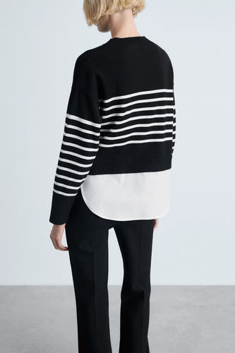 Zwarte trui met ronde hals van MANGO, gestreept ontwerp met wit, gecombineerd met een wit overhemd en zwarte broek.