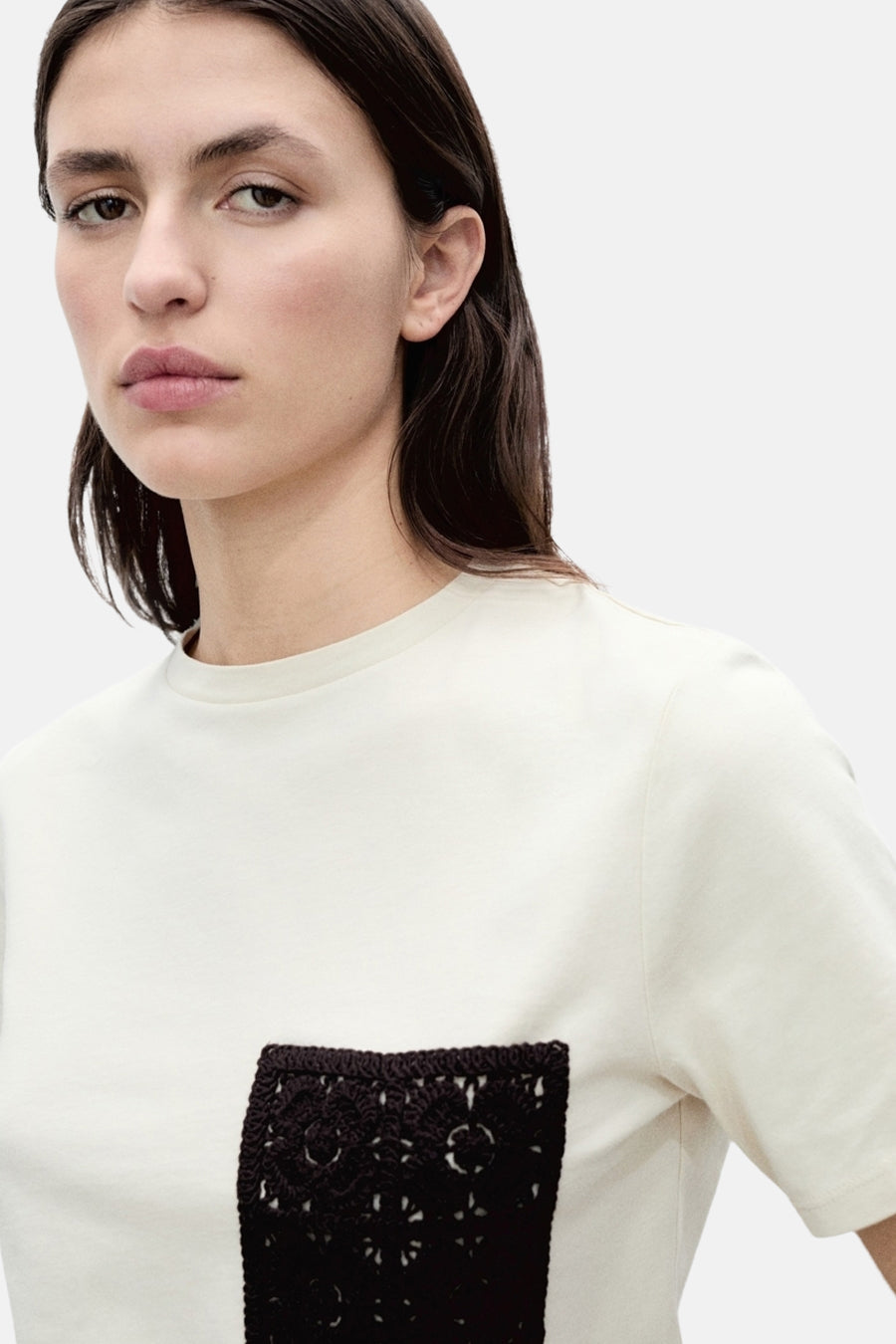 Beige T-shirt met korte mouwen van MANGO, met gehaakte zak en neutrale achtergrond.
