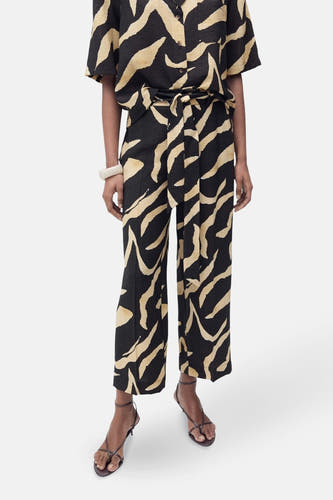 Pantalon noir de MANGO, avec un imprimé zèbre abstrait beige et une cecece correspondante.