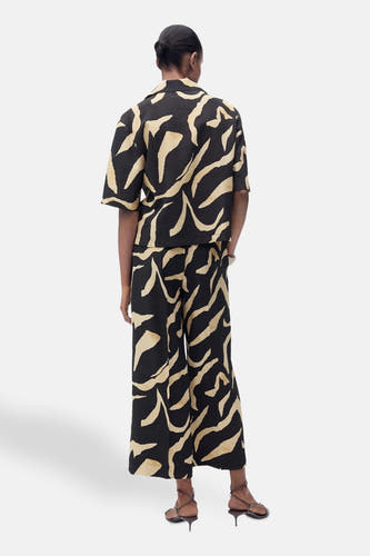 Pantalon noir de MANGO, avec imprimé zèbre beige et larges pinces, vu de derrière.