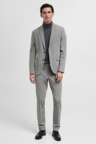 Blazer gris de MANGO porté avec un gilet gris foncé et un pantalon gris, avec des chaussures noires en cuir.