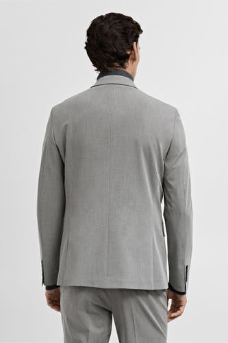Grijze blazer van MANGO, gezien van achteren met een subtiele textuur en een donkergrijze coltrui.