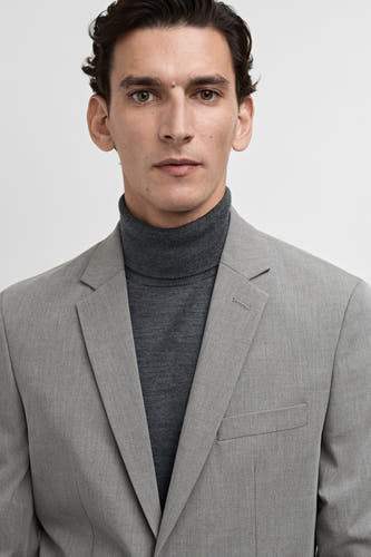 Blazer gris de MANGO, porté avec un gilet gris.