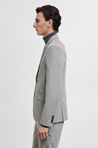 Blazer gris de MANGO, vue latérale, porté sur un gilet gris, avec quatre boutons sur la manche.