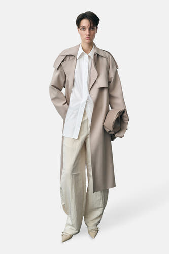 Pantalon écru de MANGO, associé à une blouse blanche et un manteau beige.